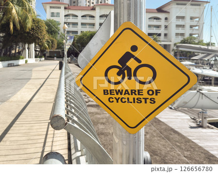 Yellow warning sign for cyclists near marina in Penang Malaysia highlighting safety for pedestrians Yellow warning sign for cyclists near marina in Penang Malaysia highlighting safety for pedestrians 126656780