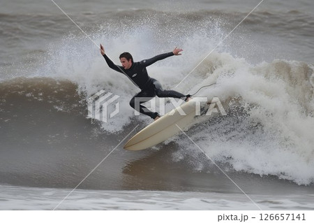 Extreme Surfing Action: Man Riding a Wave on a Surfboard in Wetsuit 126657141