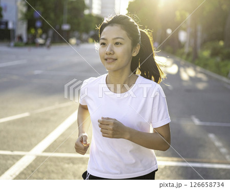 夕暮れの街を走る笑顔の女性｜健康的なライフスタイル 126658734