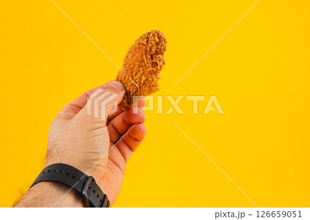 Lviv Ukraine 05.21.25 Hand holding crispy fried chicken against bright background 126659051
