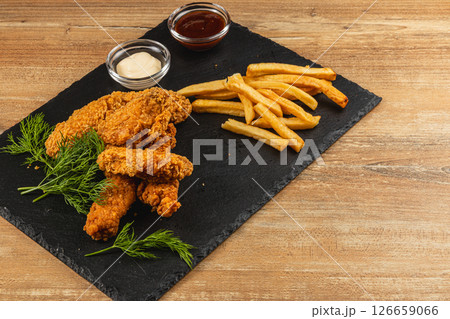 Crispy fried chicken and golden fries on a slate platter Crispy fried chicken and golden fries on a slate platter 126659066