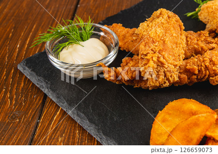 Fried chicken tenders with dipping sauce and sweet potato chips Fried chicken tenders with dipping sauce and sweet potato chips 126659073
