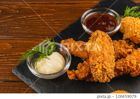 Crispy fried chicken served with sauces on a wooden table 126659079
