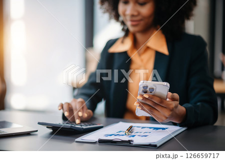 Beautiful Asian woman using laptop and tablet while sitting at her working place. Concentrated at work. Beautiful Asian woman using laptop and tablet while sitting at her working place. Concentrated at work. 126659717