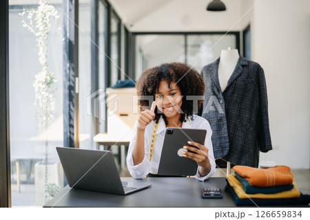 Diverse female fashion designers at work with tailor centimeters on necks and holds tablet and smartphone. 126659834