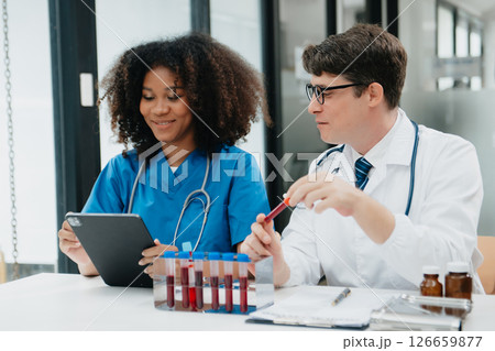 Two scientist or medical technician working, having a medical discuss meeting with an Asian senior female scientist supervisor in the laboratory with online reading, test samples 126659877