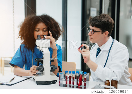 Two scientist or medical technician working, having a medical discuss meeting with an Asian senior female scientist supervisor in the laboratory with online reading, test samples Two scientist or medical technician working, having a medical discuss meeting with an Asian senior female scientist supervisor in the laboratory with online reading, test samples 126659934