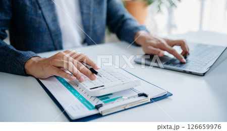 Women counting coins on calculator taking from the piggy bank. hand holding pen working on calculator to calculate on desk about cost 126659976