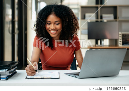 Young woman typing on tablet and laptop while sitting at the working in office 126660228