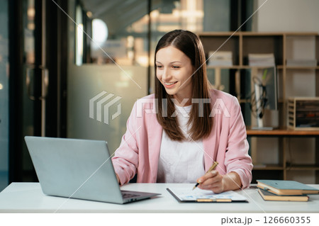 Business expert attractive smiling young woman typing laptop and holding digital tablet 126660355
