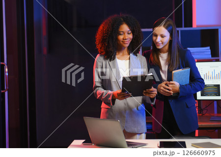 Two business workers talking on the smartphone and using laptop at the office. overtime Two business workers talking on the smartphone and using laptop at the office. overtime 126660975