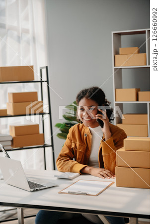 Young African woman running online store Startup small business SME, using smartphone or tablet taking receive and checking online purchase shopping order 126660992