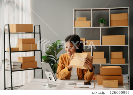Young African woman running online store Startup small business SME, using smartphone or tablet taking receive and checking online purchase shopping order Young African woman running online store Startup small business SME, using smartphone or tablet taking receive and checking online purchase shopping order 126660995