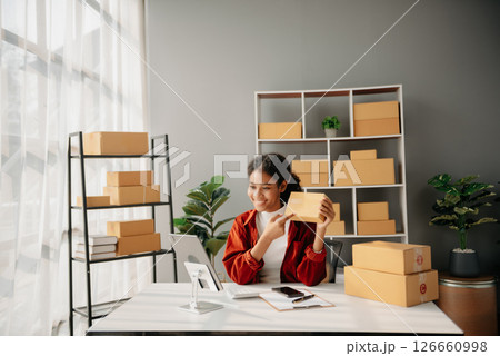 Young African woman prepare parcel box and standing check online orders for deliver to customer on tablet, laptop Shopping Online concept. Young African woman prepare parcel box and standing check online orders for deliver to customer on tablet, laptop Shopping Online concept. 126660998