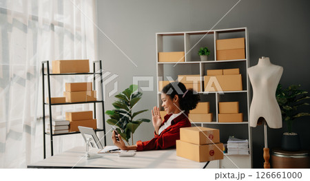 Young African woman running online store Startup small business SME, using smartphone or tablet taking receive and checking online purchase shopping order 126661000