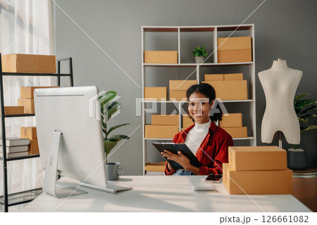Young African woman running online store Startup small business SME, using smartphone or tablet taking receive and checking online purchase shopping order 126661082