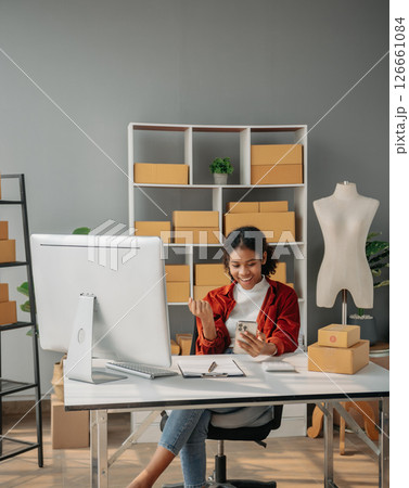 Young African woman running online store Startup small business SME, using smartphone or tablet taking receive and checking online purchase shopping order 126661084