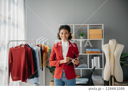 Diverse female fashion designers at work with tailor centimeters on necks and holds tablet and smartphone. independent creative design business. Diverse female fashion designers at work with tailor centimeters on necks and holds tablet and smartphone. independent creative design business. 126661086