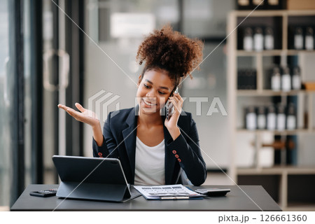 Beautiful Asian woman using laptop and tablet while sitting at her working place. Concentrated at work. 126661360