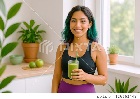 Indigenous young woman holding green smoothie indoors, healthy lifestyle concept 126662448