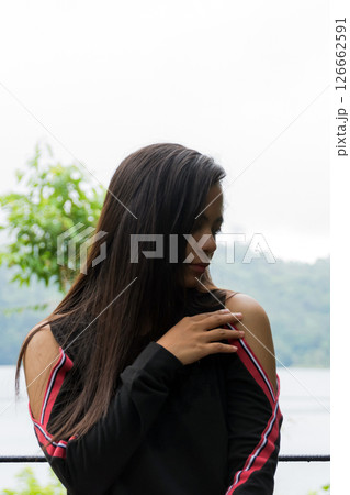 Thoughtful young asian woman with long hair by the lake in the mountains 126662591