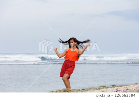 Joyful asian young woman in swimsuit dancing on ocean shore 126662594