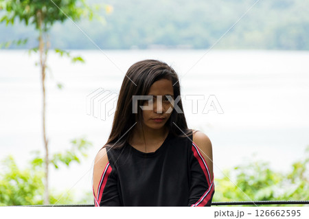 Thoughtful young asian woman with long hair by the lake in the mountains 126662595