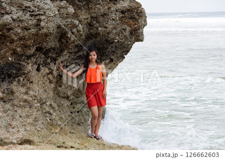 Young woman standing in tropical sea with cliffs behind Young woman standing in tropical sea with cliffs behind 126662603