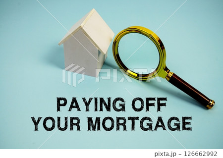 Paying Off Your Mortgage text with White Model House and magnifying glass on blue background Paying Off Your Mortgage text with White Model House and magnifying glass on blue background 126662992