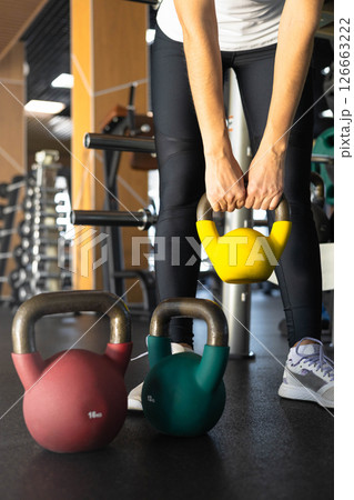 Athletic bodybuilding sport woman squat with kettlebell fitness training at gym.  126663222