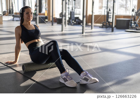 Strong fitness woman asian trains gluteal muscles, massaging herself with self-massage roller Strong fitness woman asian trains gluteal muscles, massaging herself with self-massage roller 126663226