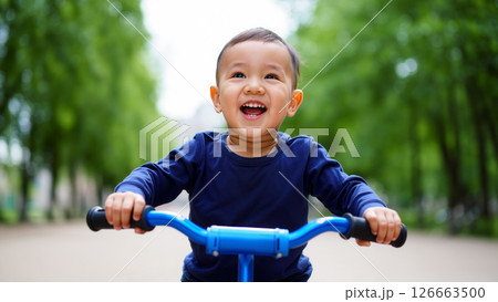 Happy Child Riding a Blue Bicycle Through a Lush Green Park on a Sunny Day 126663500