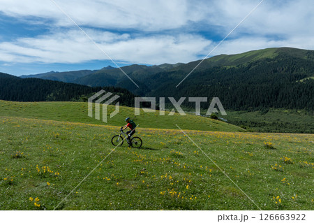 Woman riding mountain bike on beautiful flowering grassland mountain top 126663922