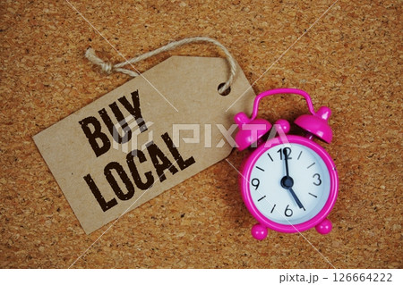 Buy Local text on price tag with alarm clock on cork board background 126664222