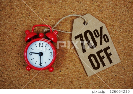 Sale 70% Off text on price tag with alarm clock on cork board background Sale 70% Off text on price tag with alarm clock on cork board background 126664239