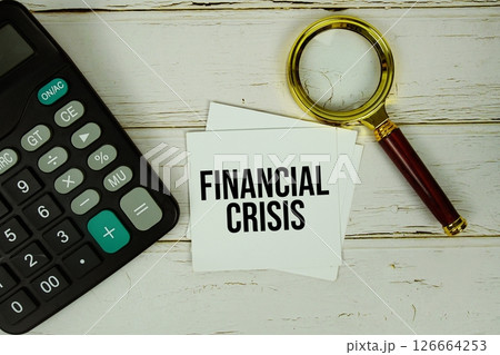 Financial Crisis text message on sticky note with magnifying glass and calculator on wooden background Financial Crisis text message on sticky note with magnifying glass and calculator on wooden background 126664253