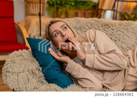 Adult woman waking up scared from nightmare on sofa at home, showing fear emotional shock expression Adult woman waking up scared from nightmare on sofa at home, showing fear emotional shock expression 126664361