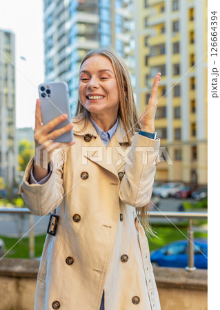Happy businesswoman using smartphone celebrating victory win message news on downtown city street Happy businesswoman using smartphone celebrating victory win message news on downtown city street 126664394