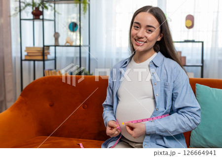 Pregnant woman measuring belly diameter with measure tape awaiting childbirth monitoring body change Pregnant woman measuring belly diameter with measure tape awaiting childbirth monitoring body change 126664941