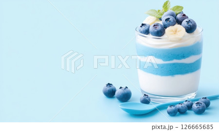 Delightful layered parfait featuring blue yogurt and fresh berries in an elegant glass setting with a matching spoon 126665685