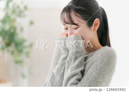 両手の袖で顔を隠す女性 126665992