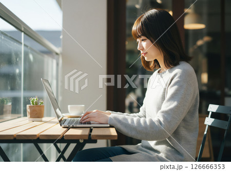 カフェでノートパソコンを使って作業する20代女性 126666353