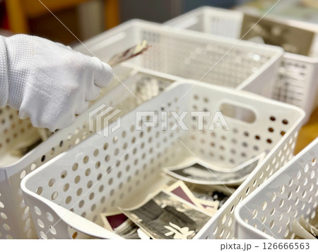 ケースに白黒写真を仕分けする白手袋の手元 126666563