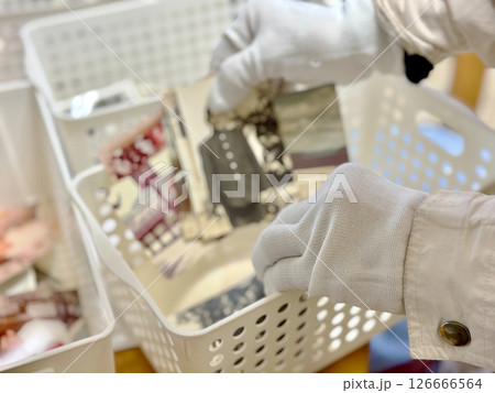 ケースに白黒写真を入れる白手袋の手元 126666564