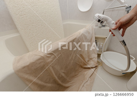 浴室でシャワーを使ってマットレスと布団カバーを洗っている 126666950