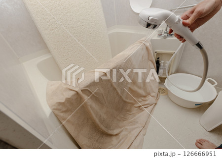 浴室でシャワーを使ってマットレスと布団カバーを洗っている 126666951