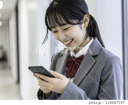 スマホを見て笑顔を浮かべる女子高生の横顔 126667597