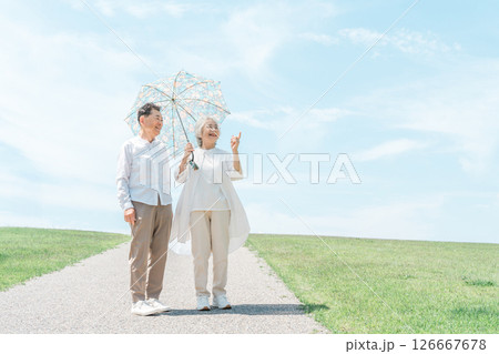 日傘をさして公園を散歩するシニア夫婦 日傘をさして公園を散歩するシニア夫婦 126667678