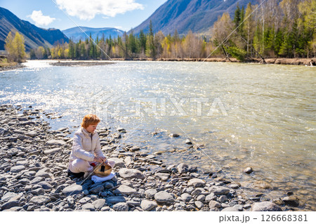 Woman performing a sound ritual with a Tibetan singing bowl by the Altai river. Concept of feminine energy, sacred vibration, and shamanic connection to the Earth Woman performing a sound ritual with a Tibetan singing bowl by the Altai river. Concept of feminine energy, sacred vibration, and shamanic connection to the Earth 126668381