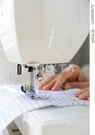 woman sews a light fabric on a sewing machine. making clothes, hobbies. 126669072